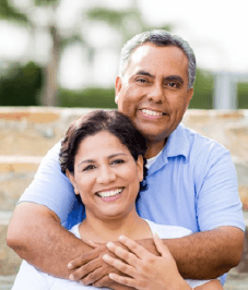 An older couple hugging and smiling outside