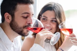 man and woman smiling drinking wine