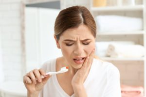 Pained woman holding toothbrush with bad bushing habits