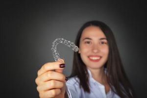 Woman holding aligner for Invisalign in Philadelphia. 